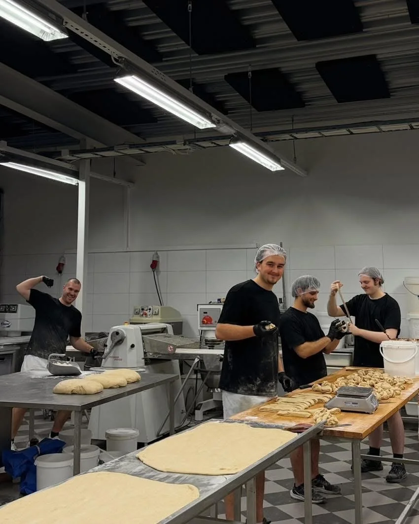Bakerne arbeider med deig ved bakerbenken